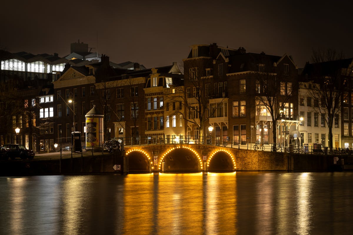 Canal bridge lit up at night in Amsterdam