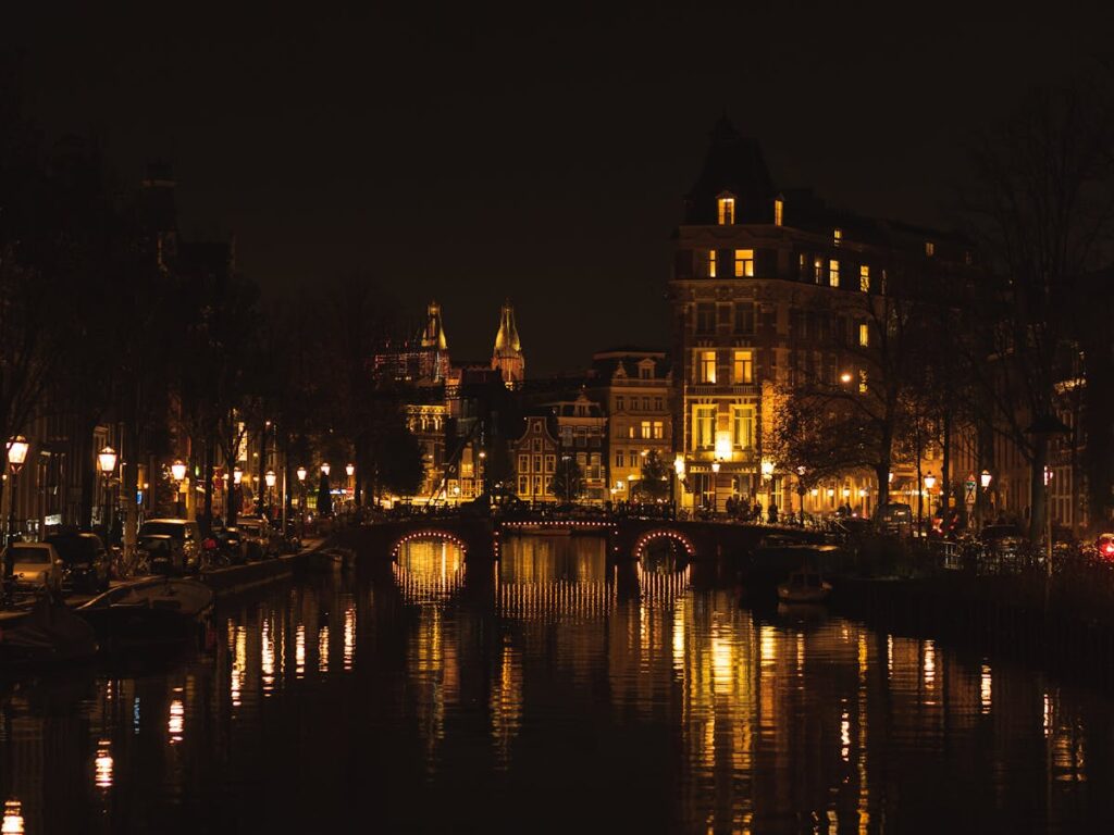 Amsterdam canal houses lit up at night with reflections in the water